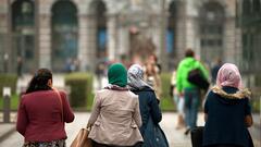 Four young women seen from behind, three of whom are wearing headscarves, walk through Antwerp, Belgium, 2013