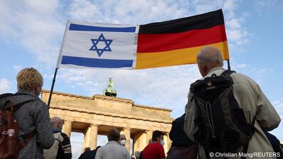 People carry an Israeli and a German flag that have been joined together during a rally in solidarity with Israel and against antisemitism, in front of the Brandenburg Gate in Berlin, Germany, 20 May 2021