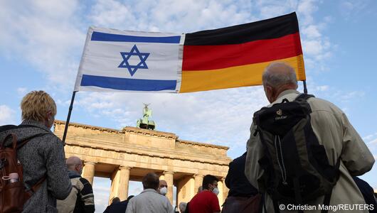 People carry an Israeli and a German flag that have been joined together during a rally in solidarity with Israel and against antisemitism, in front of the Brandenburg Gate in Berlin, Germany, 20 May 2021