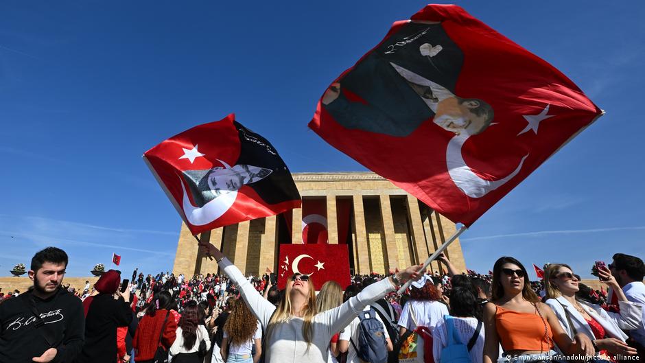 A woman waves two Turkish flags bearing Ataturk's likeness in front of his mausoleum in Anitkabir