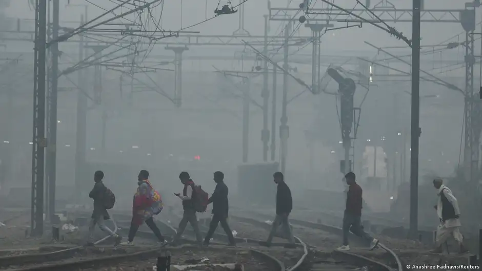 People cross railway tracks on a smoggy morning in Delhi