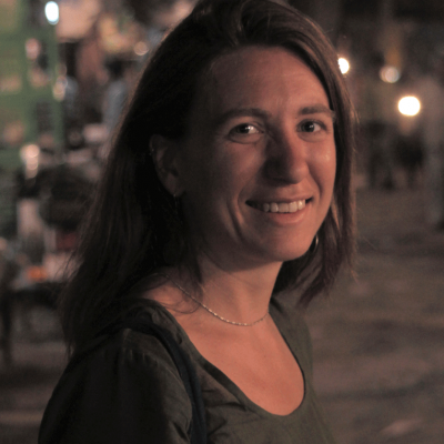 Headshot of a woman with dark hair against an evening urban scene