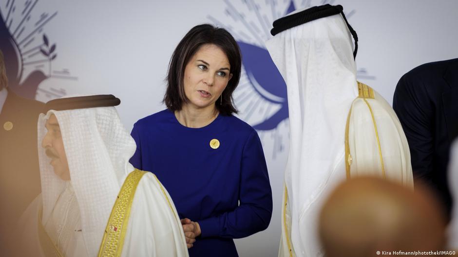 German Foreign Minister Annalena Baerbock in blue talks to a man in Arab dress at the Cairo Peace Summit