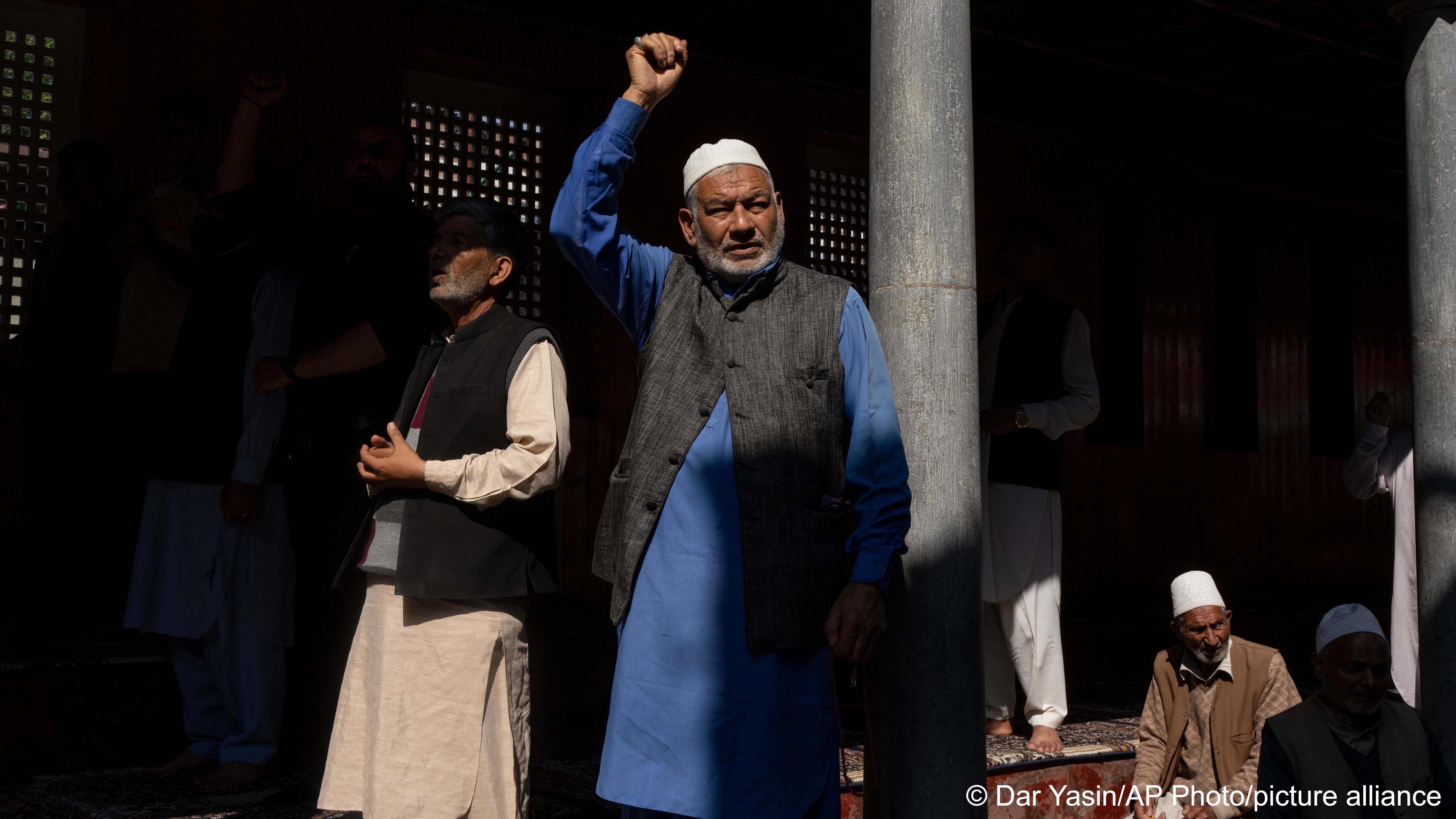 An elderly Muslim Kashmiri waves his arm, shouting slogans