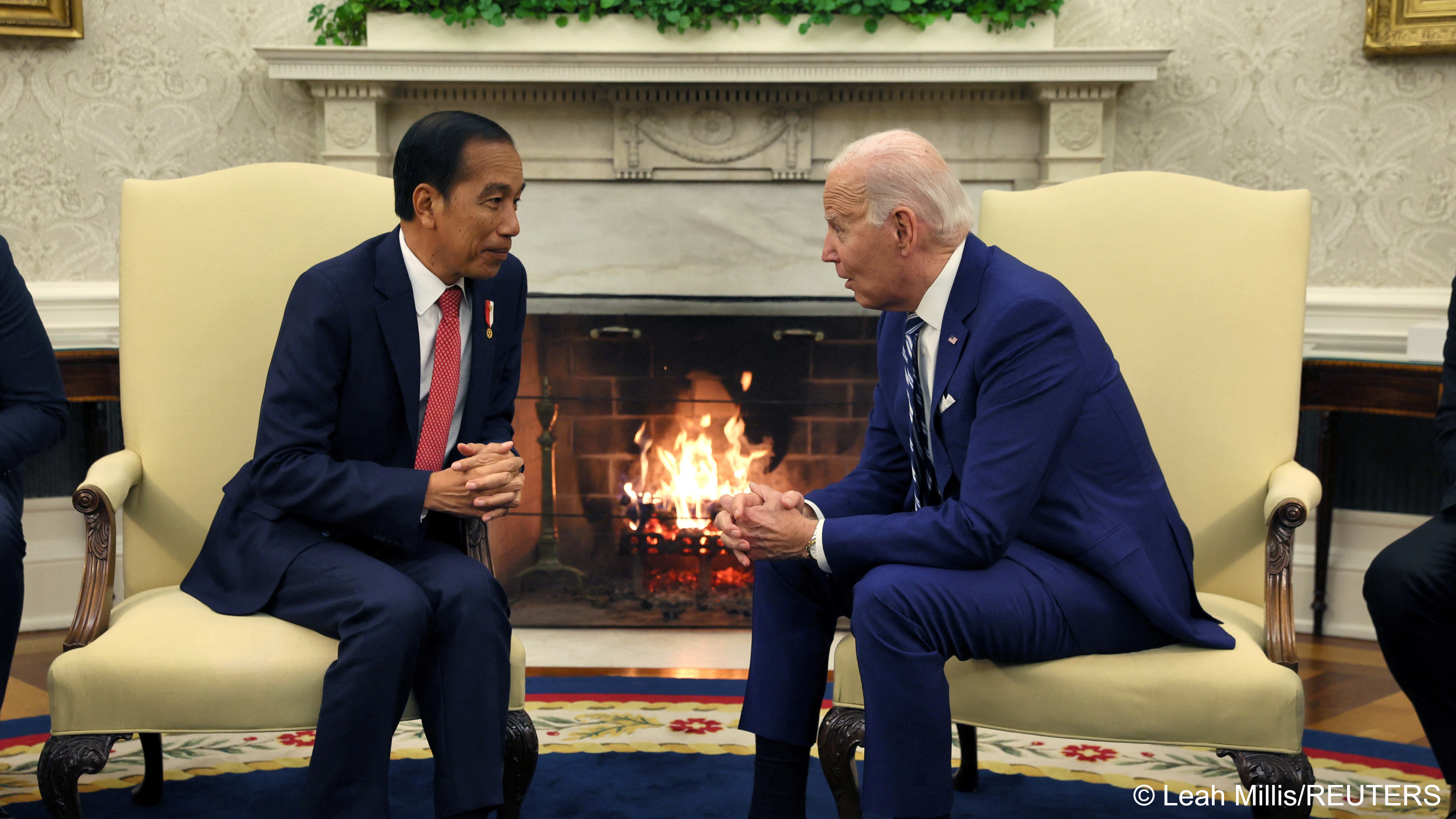 Indonesian President Joko Widodo and U.S. President Joe Biden sit in armchairs either side of a fireplace in the White House