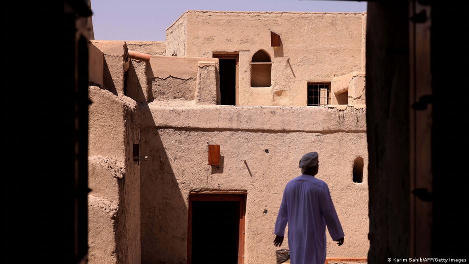 Man walks through a narrow street between mudbrick walls