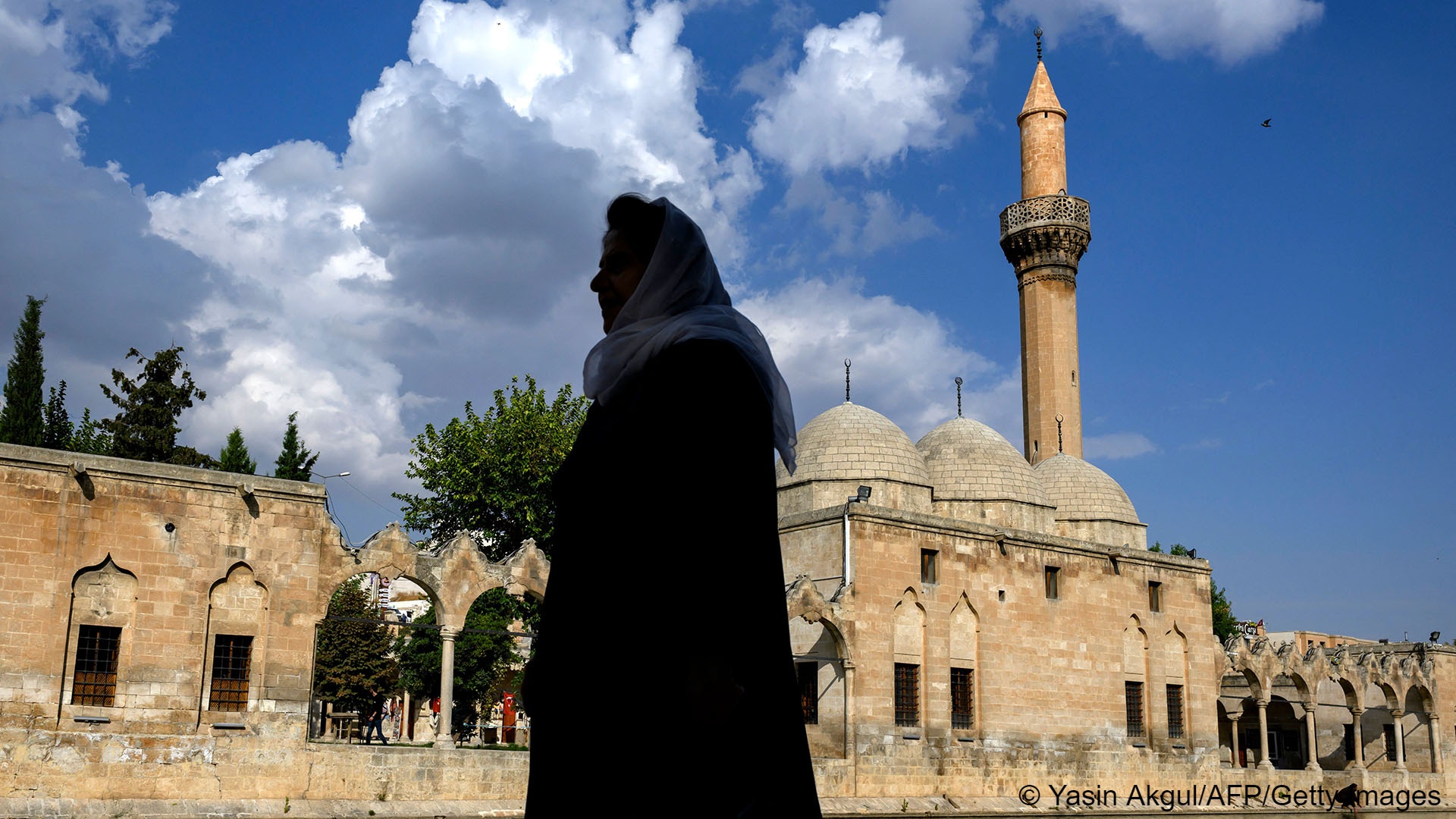 Silhouette of a woman against the background of Ottoman architecture, a minaret and a cloudy blue sky