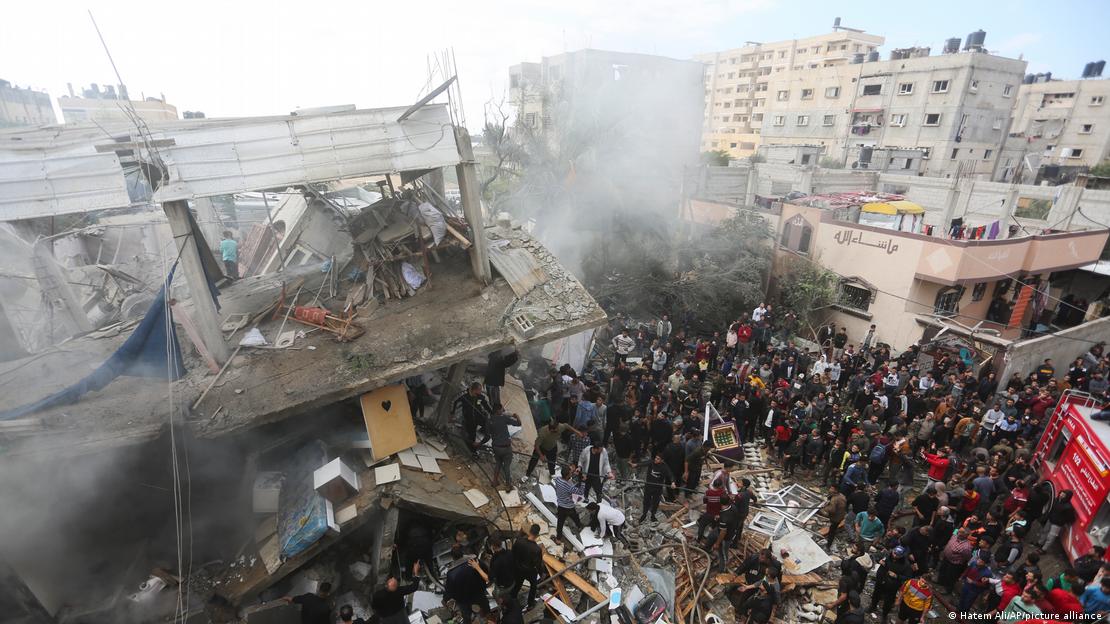 A crowd watches as people look for survivors in a severely damaged building after an Israeli air strike on Rafah, Gaza Strip, 14 November 2023