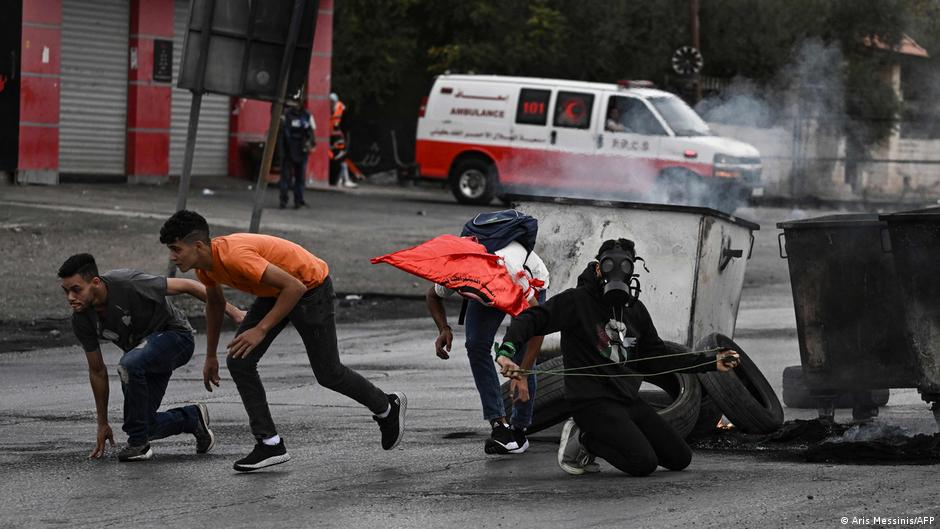 Palestinian youths take cover during a demonstration in Ramallah, West Bank