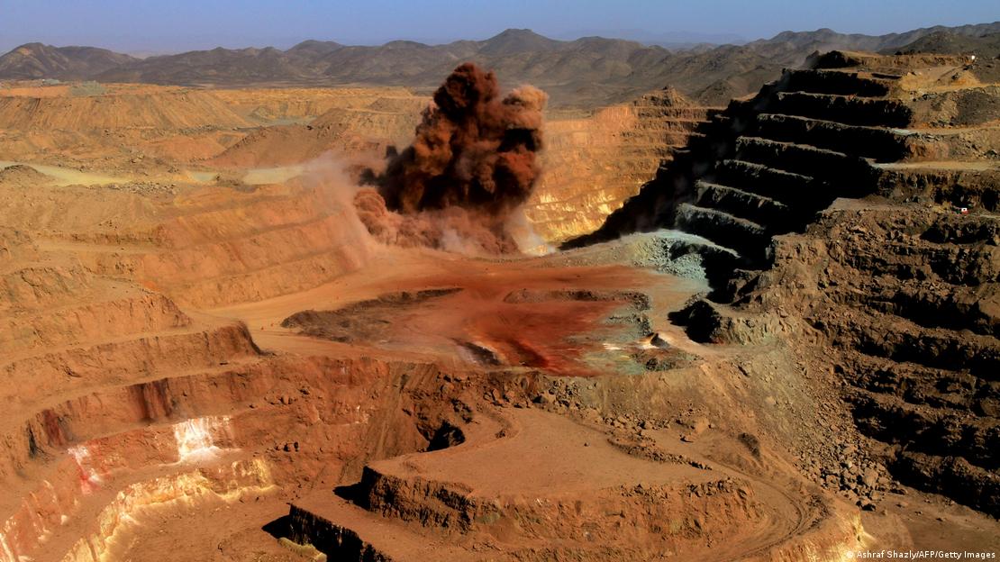 Dark orange smoke rises from the orange earth of the terraces of a gold mine in Sudan