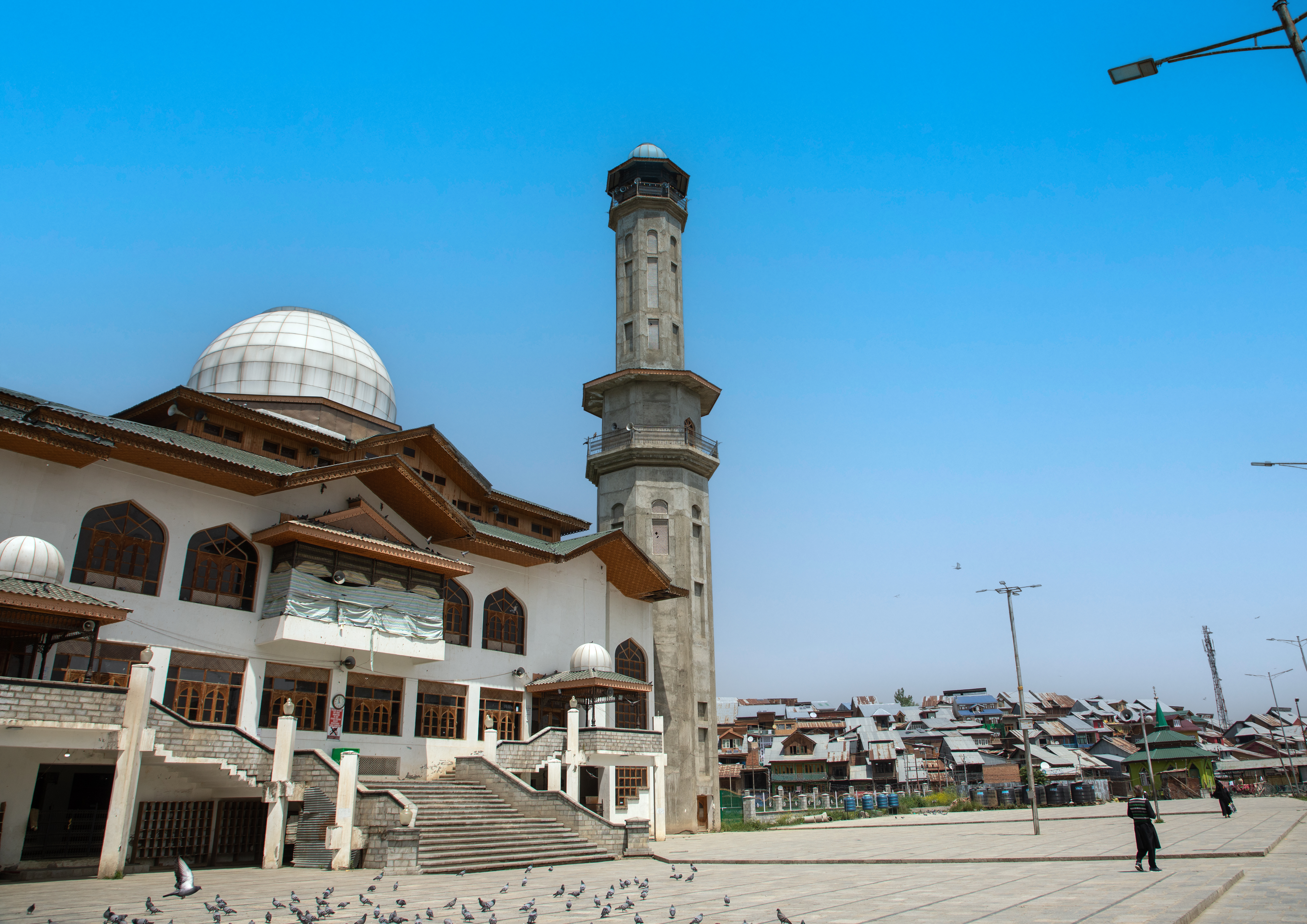 View of a mosque complex with dome and minaret against a blue sky