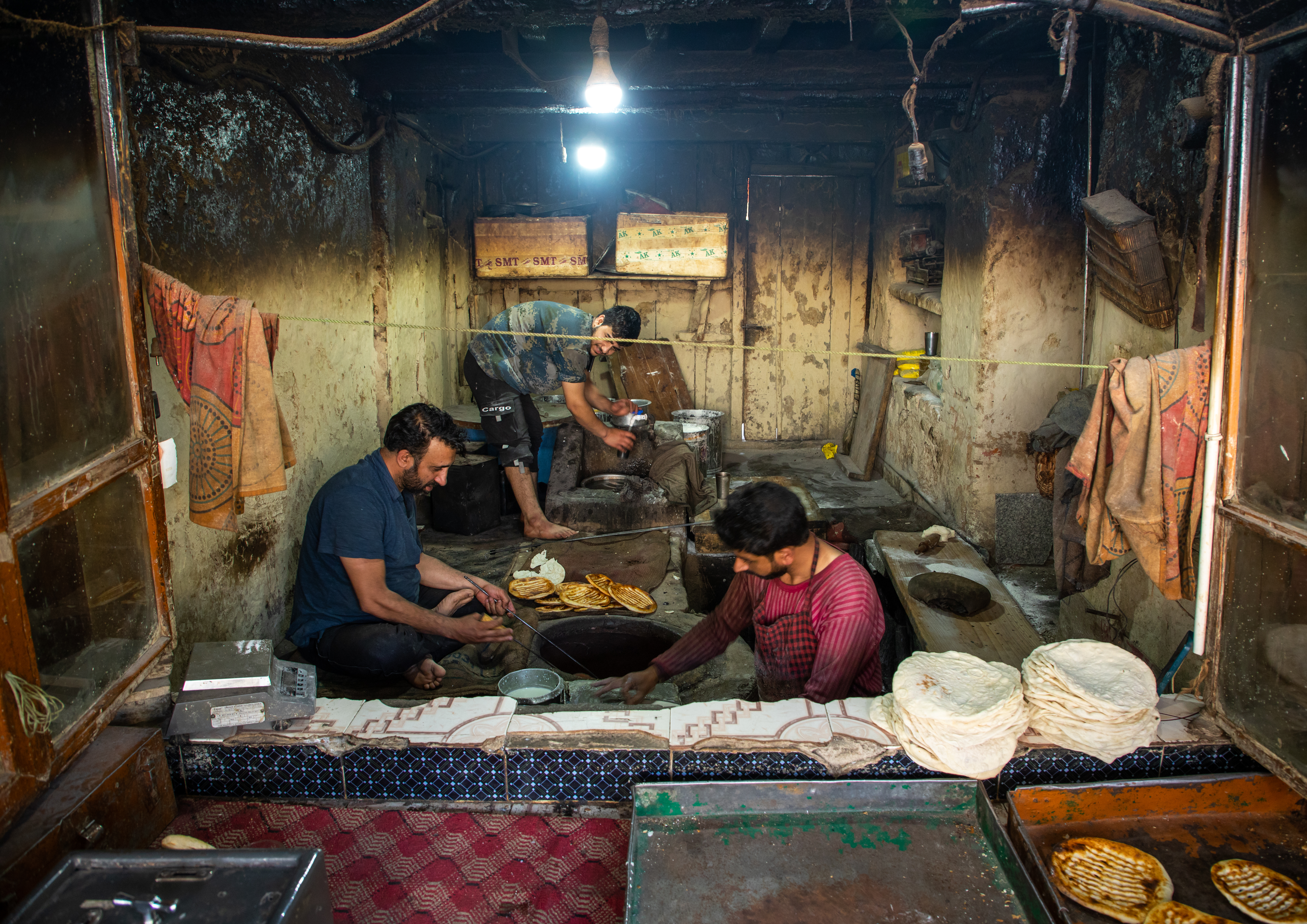 Men sit on the floor preparing traditional Kashmiri flatbreads for baking