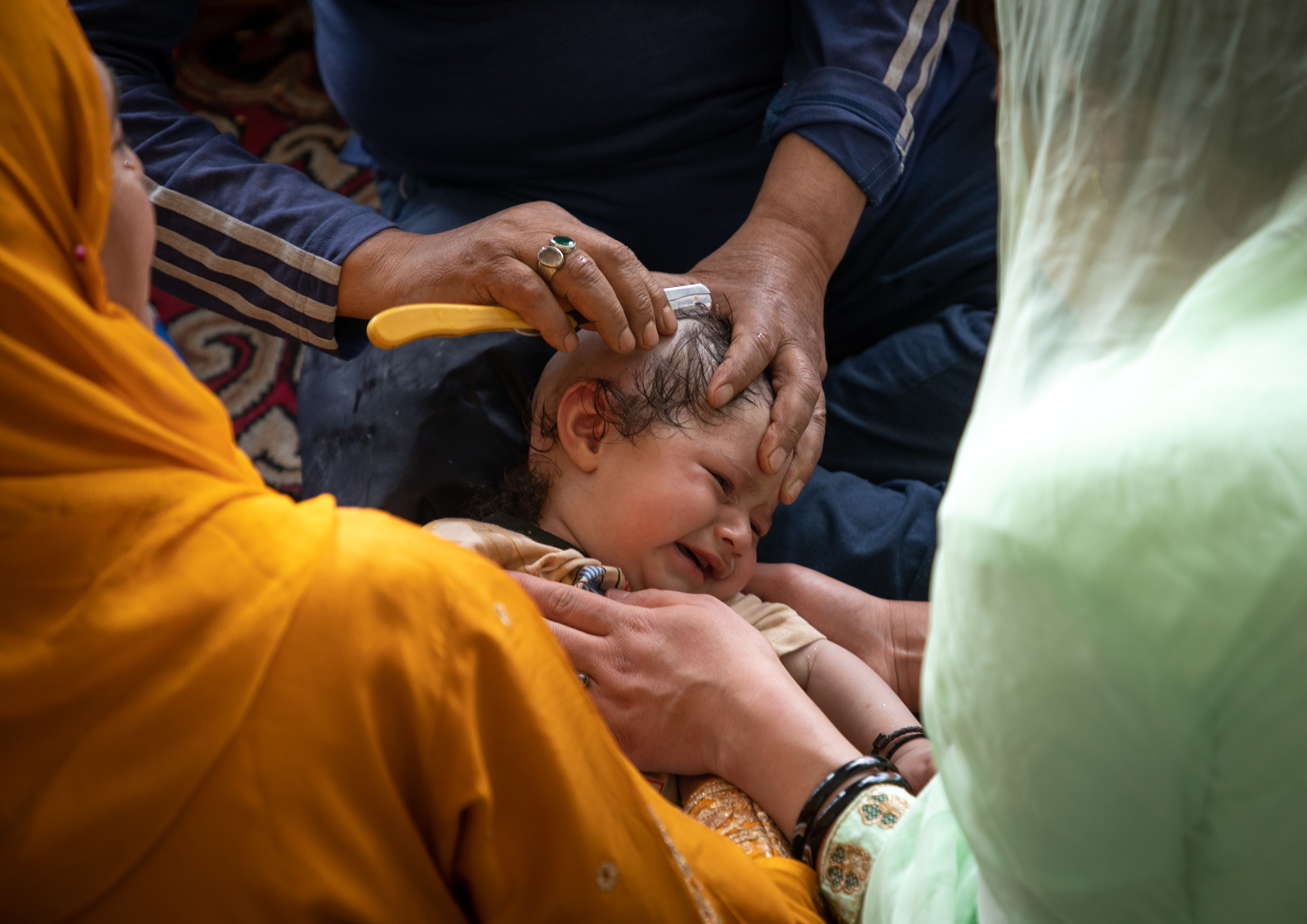An infant's head is shaved during a Sufi ritual