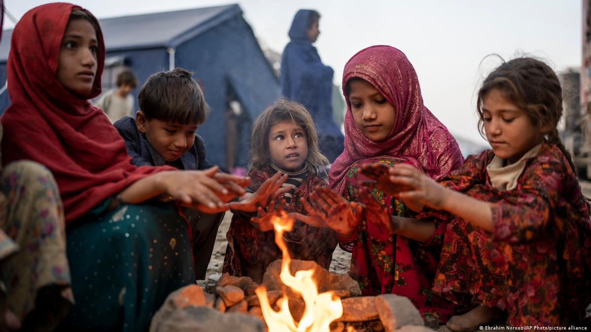 A group of five Afghan refugee children warm their hands at a fire 
