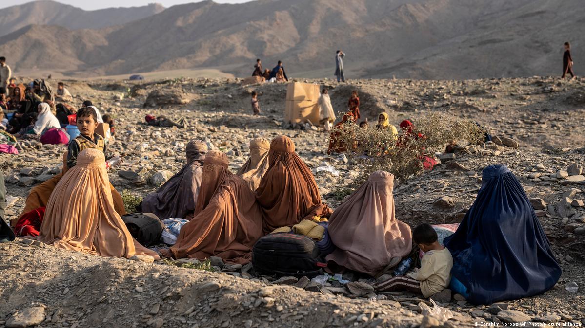 A group of women in burqas with children sit on the ground near the Afghanistan-Pakistan border in Torkham