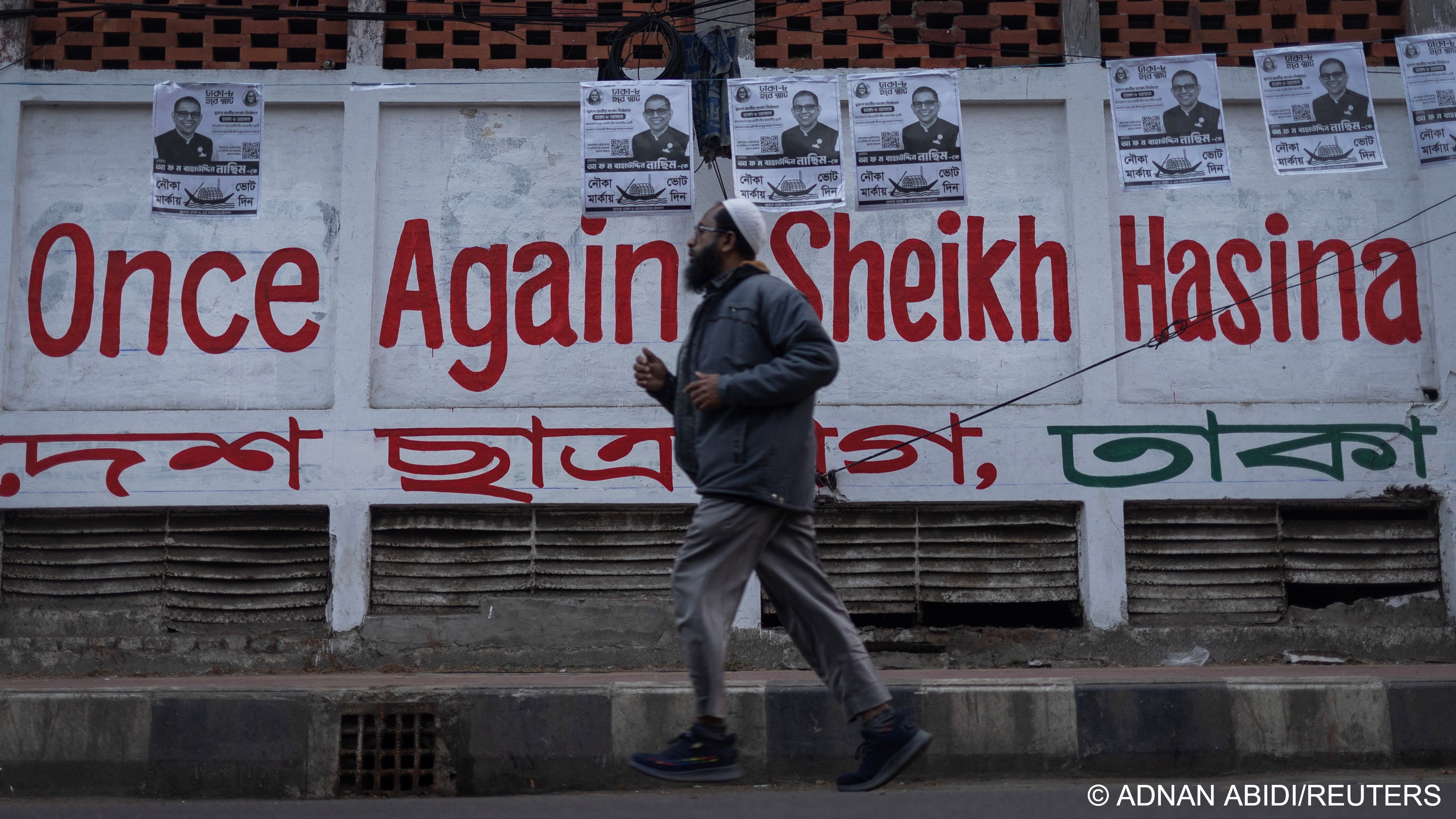 A man jogs past election campaign posters for the Awami League and the slogan 'once again Sheikh Hasina' on a street ahead of the general election on 7 January, Dhaka, Bangladesh, 4 January 2024