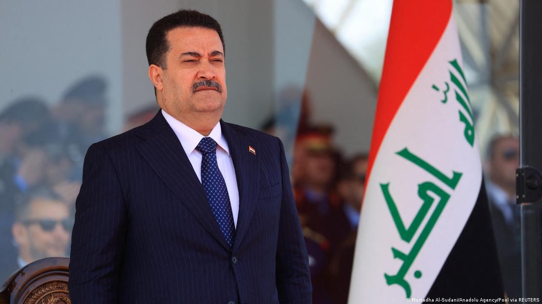 Iraqi Prime Minister Mohammed Shia al-Sudani stands next to the Iraqi flag at an event in Baghdad