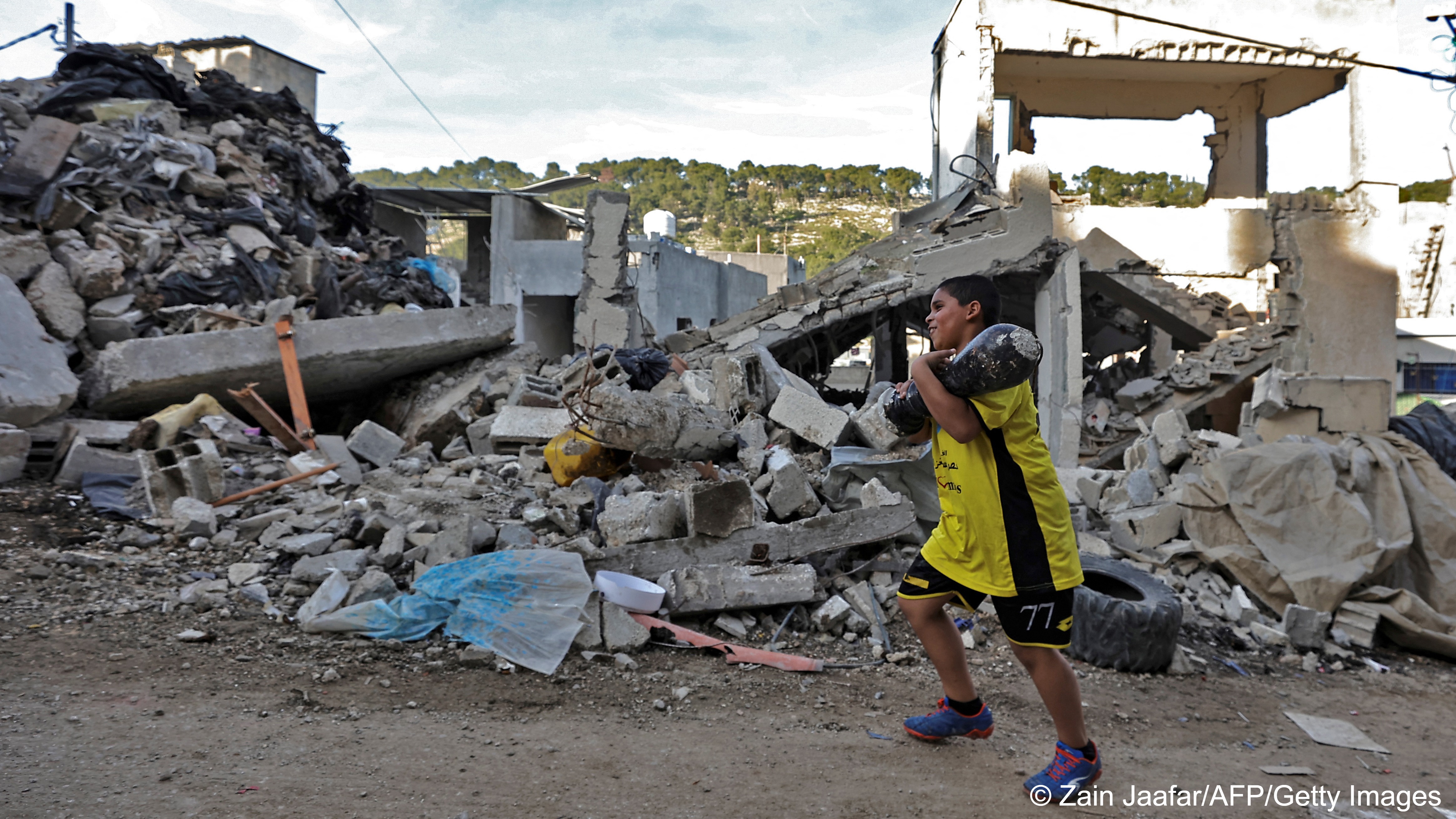 A boy walks past a ruined building in Nur Shams refugee camp, Tulkarm, West Bank