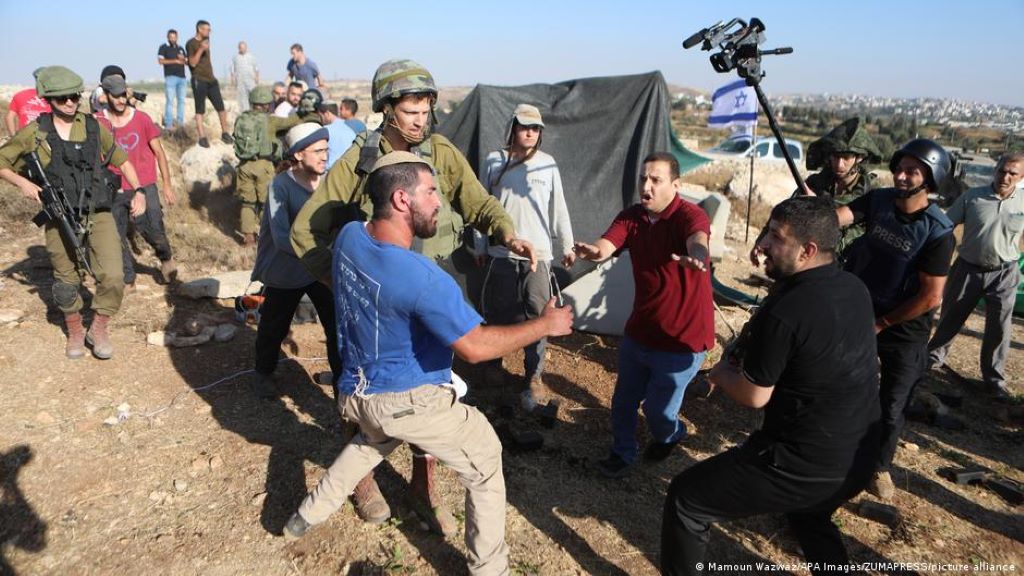 Palestinians wrestle with Israeli settlers who have set up tents in on land belonging to the village of Halhoul, north of Hebron in the occupied West Bank