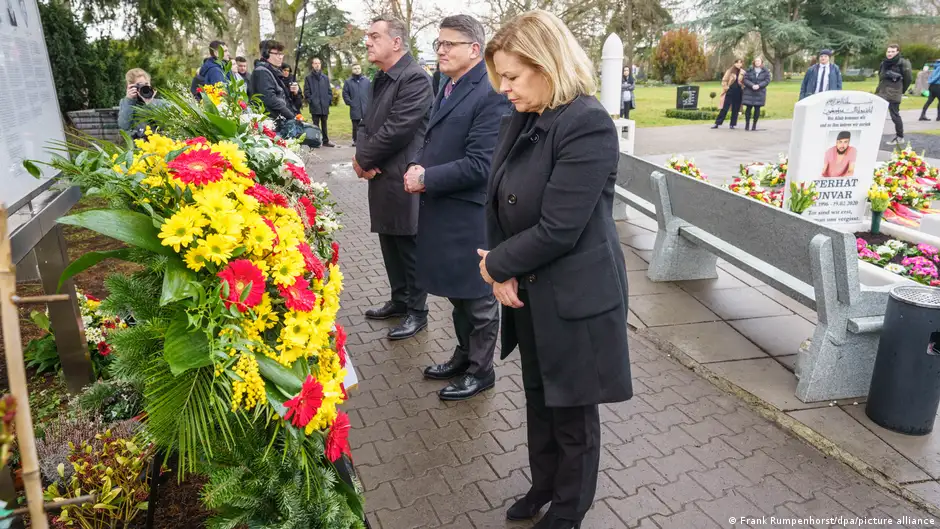 From left to right in the frame, Hanau Mayor Claus Kaminsky, Hesse state premier Boris Rhein and German Interior Minister Nancy Faeser stand in front of wreaths at the memorial site to the Hanau shooting victims