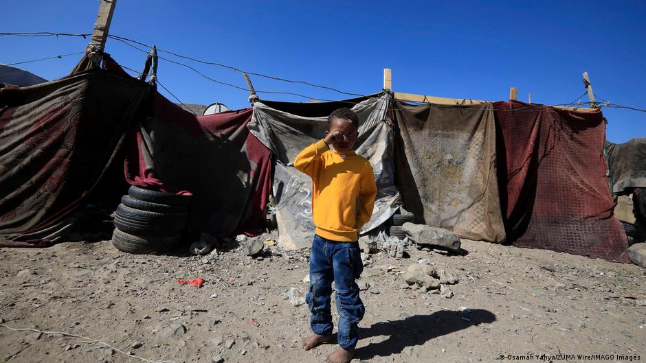 Child stands in front of a tent in a camp for internally displaced persons in Yemen