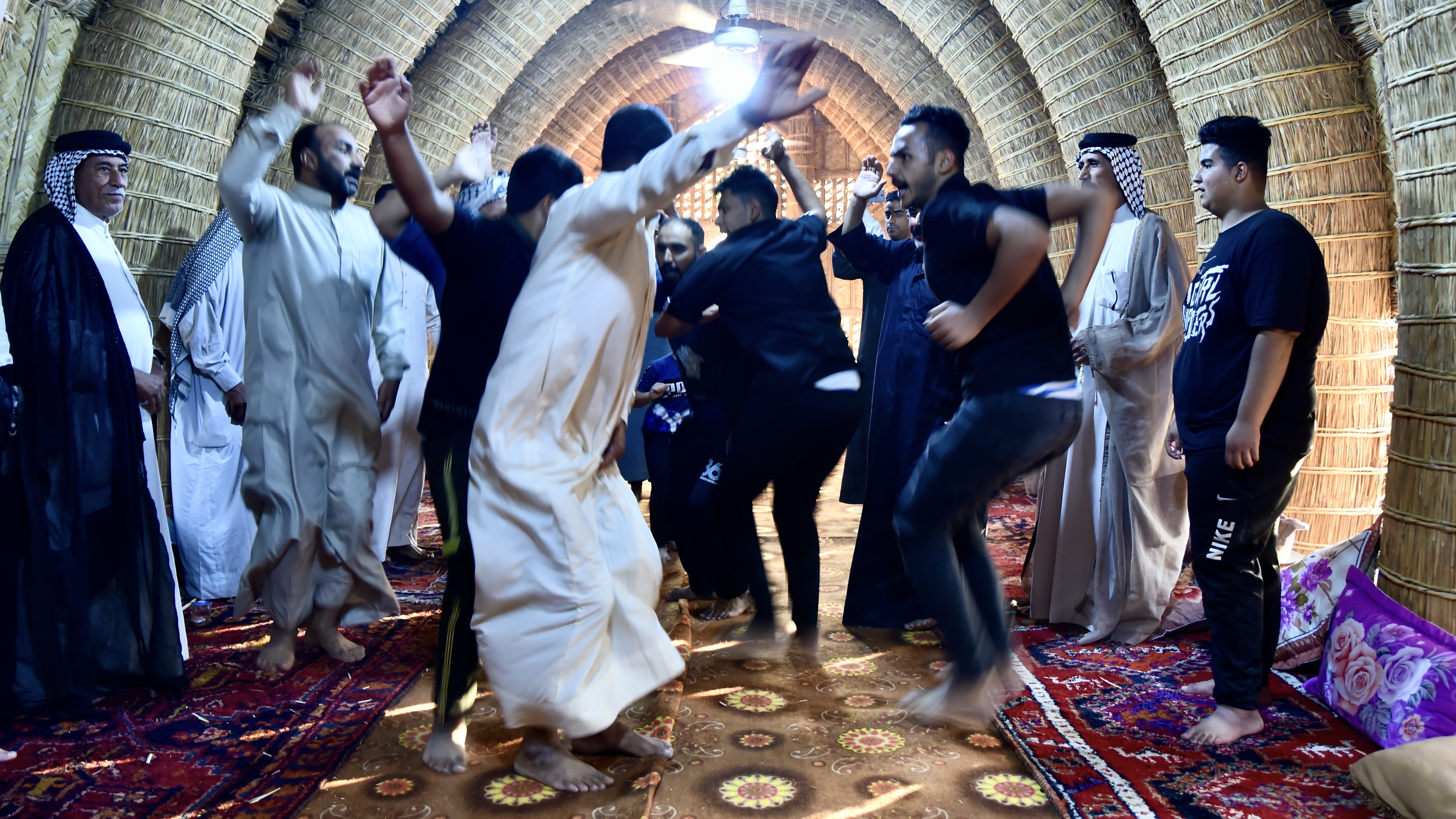 Marsh Arab men dancing in celebration inside the new mudhif