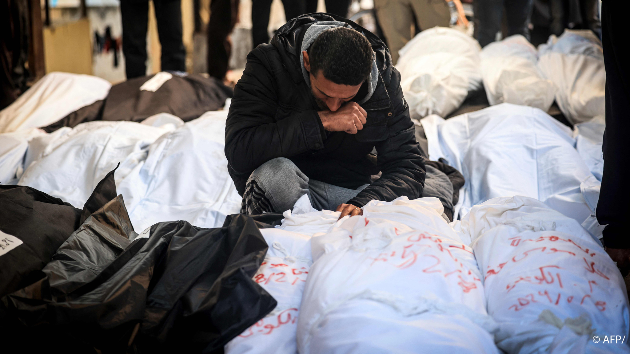 A Palestinian man mourns over shrouded bodies of relatives killed in overnight Israeli bombardment on the southern Gaza Strip at hospital in Rafah