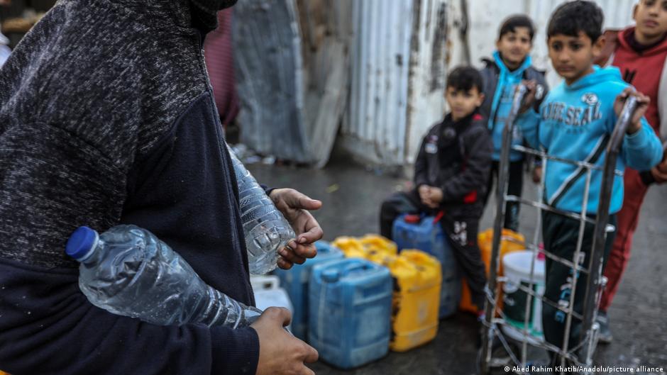 Palestinians carry containers of drinkable water collected from the mobile tankers of UN amid acute shortages of food, clean water and medicine due to Israeli attacks, in Rafah, Gaza