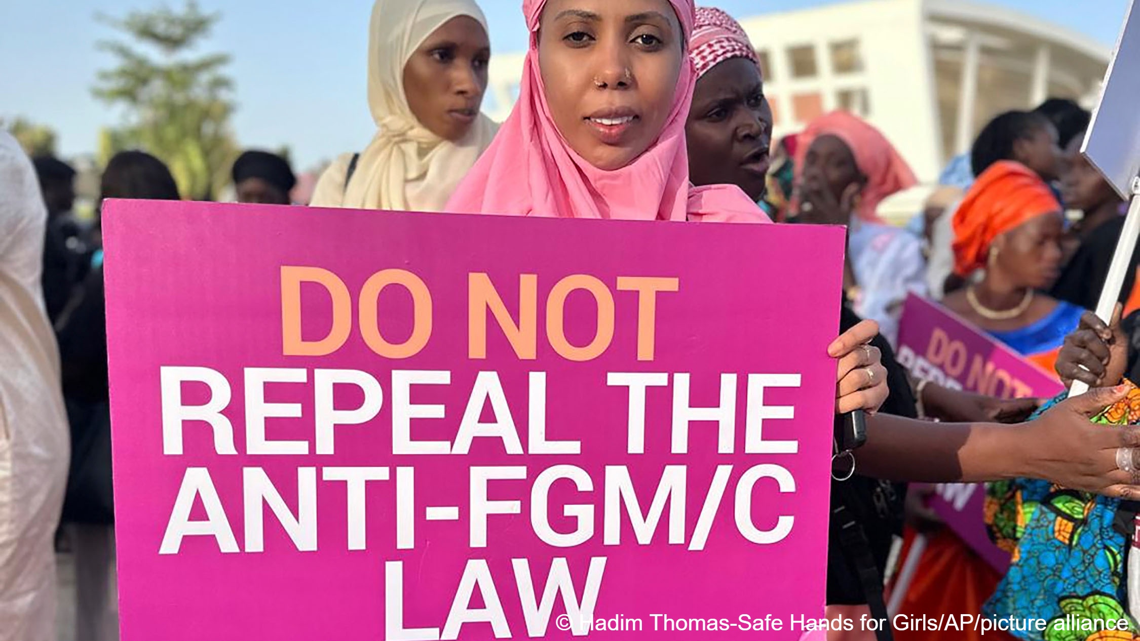 Jaha Dukureh, the founder of Safe Hands for Girls, holds up a sign that reads 'Do not repeal the anti-FGM/C law' during a demonstration outside parliament in Serrekunda, Gambia, Monday, 18 March 2024