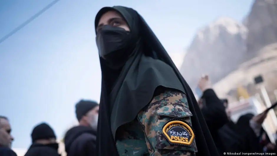 A woman in police uniform wearing a black headscarf and face covering