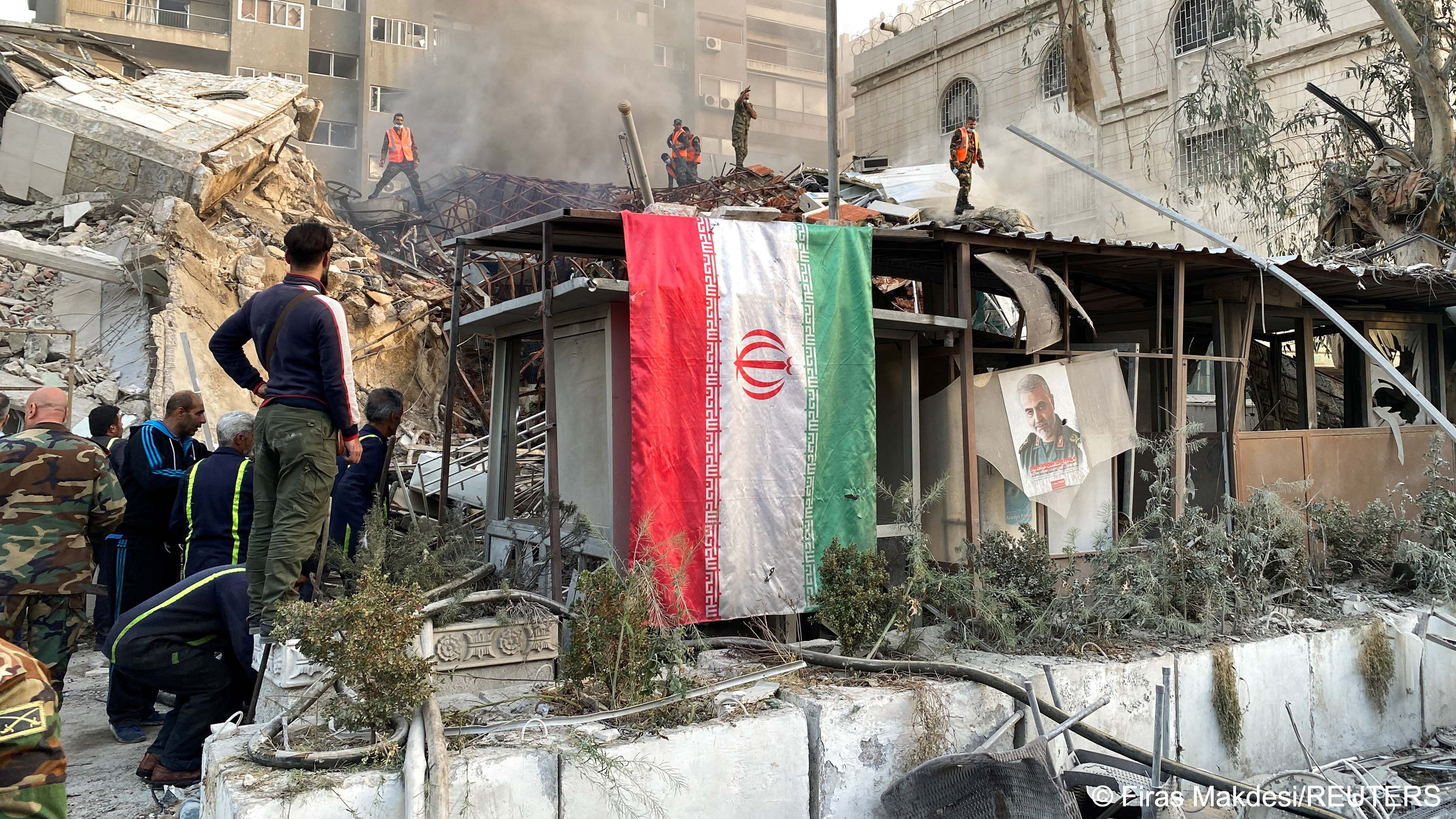 Smoke rises and an Iranian flag hangs from the ruins of a building close to the Iranian embassy in Damascus, Syria, 1 April 2024