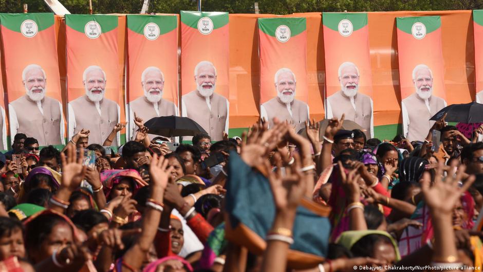 A group of Modi supporters waving against a background of Modi banners