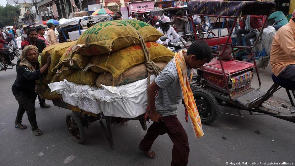 Labourers carrying a sack loaded on a cart