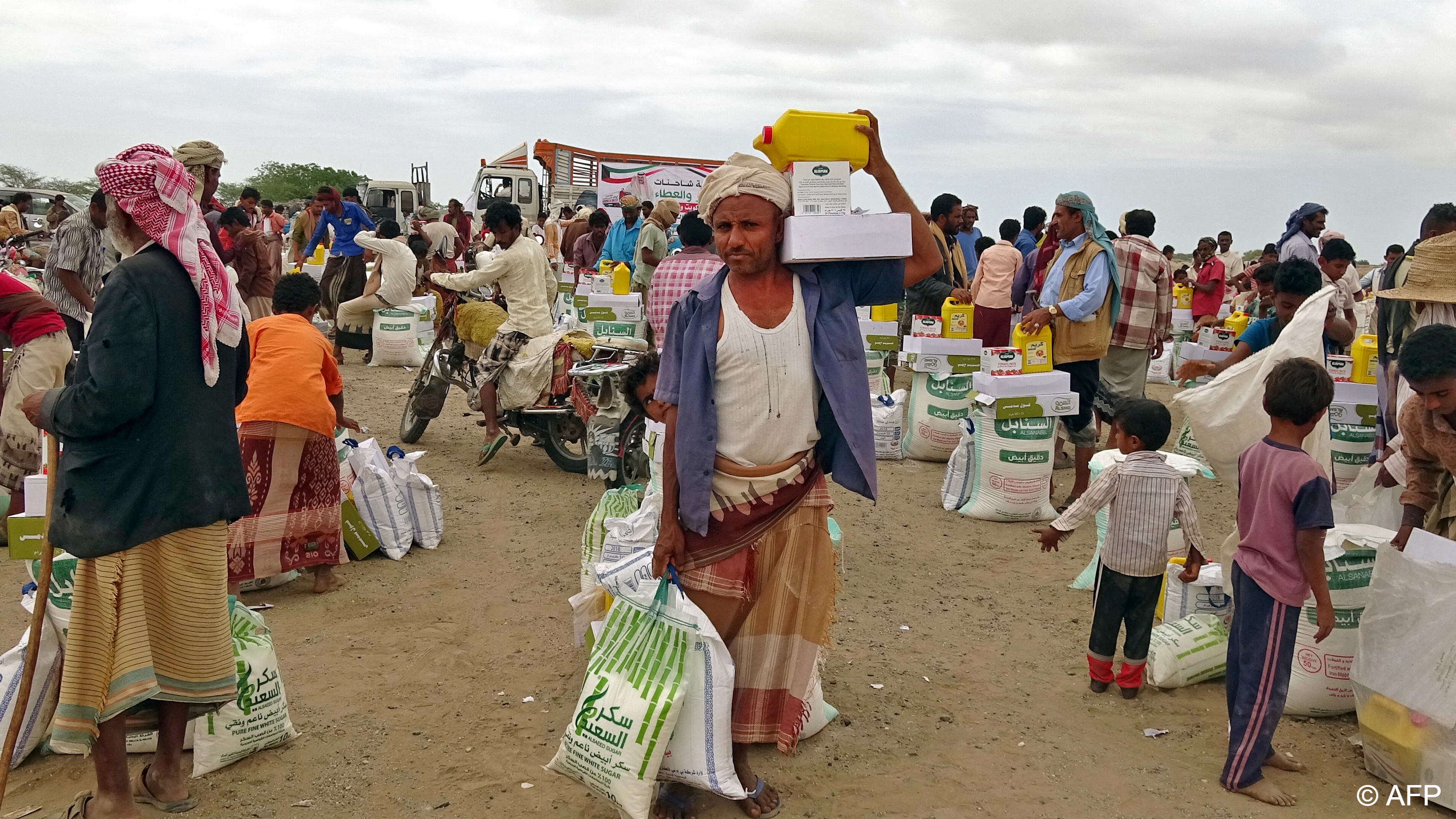 People displaced by conflict receive food aid donated by a Kuwaiti charity organisation in the village of Hays, near the conflict zone in Yemen's western province of Hodeida, 22 February 2021