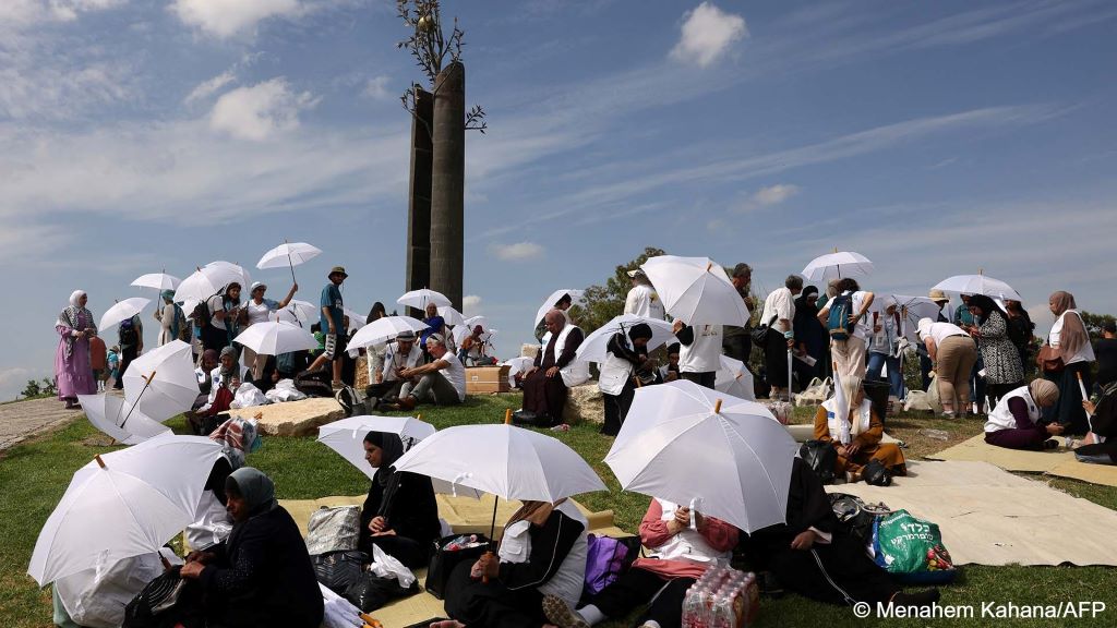 Women sit and stand beneath white umbrellas in the sun at a Women Wage Peace/Women of the Sun event on 4 October 2023
