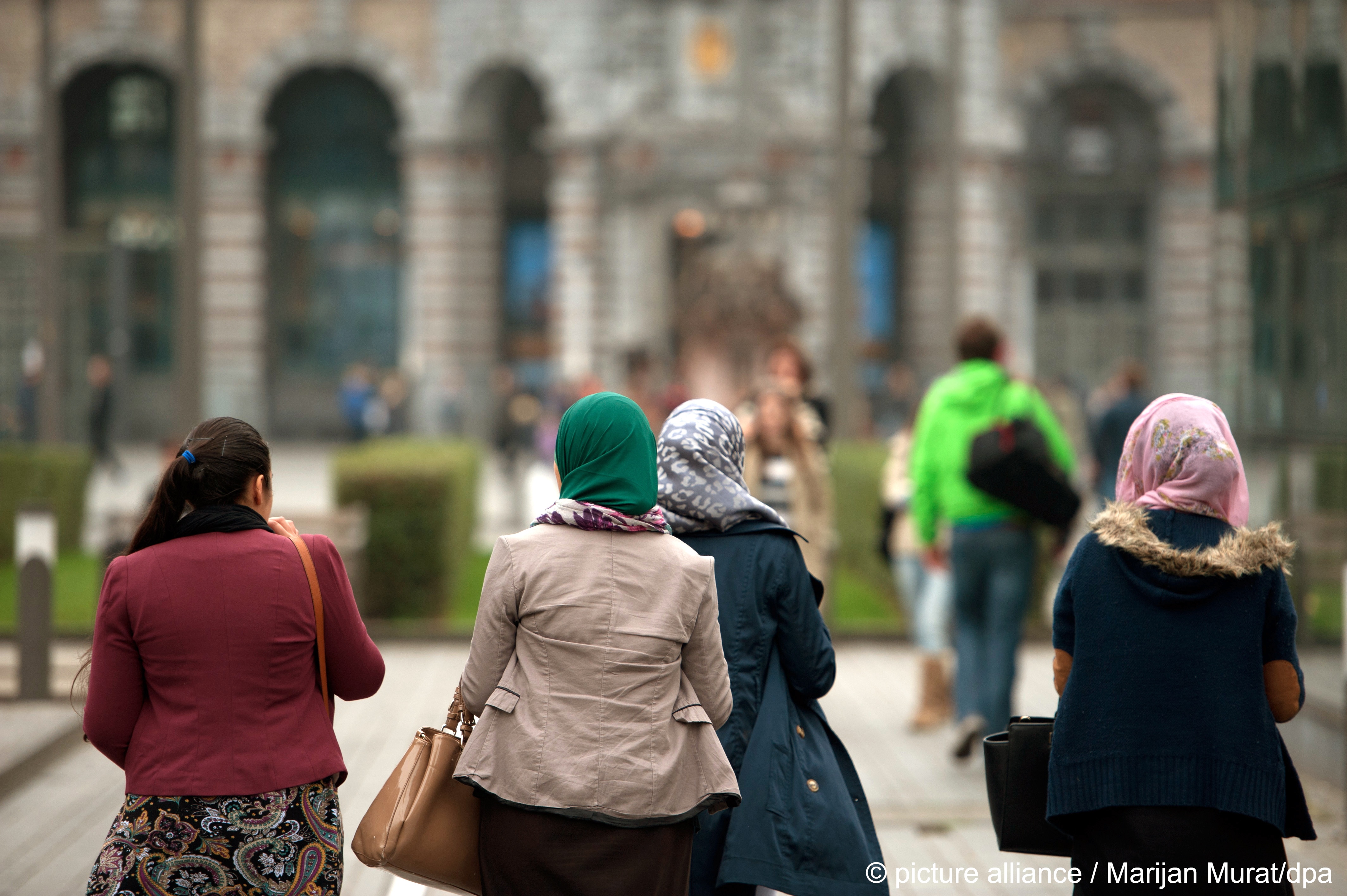 Four young women seen from behind, three of whom are wearing headscarves, walk through Antwerp, Belgium, 2013