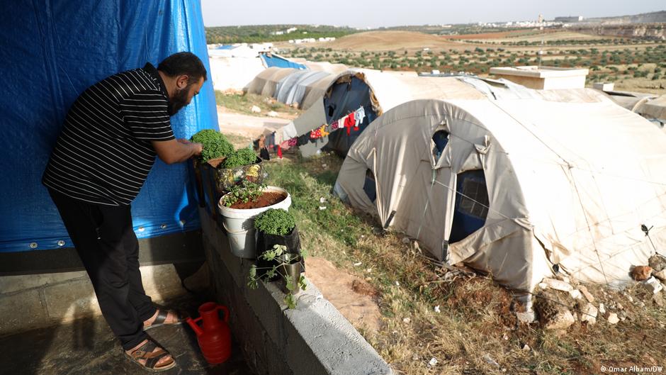 Displaced Syrian man Ramzi al-Youssef waters plants in a camp for displaced near Maarat Misrin in the north of Idlib province