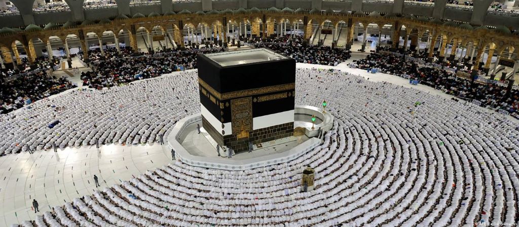Menschen beten in der Großen Moschee und verneigen sich in Richtung Kaaba 
