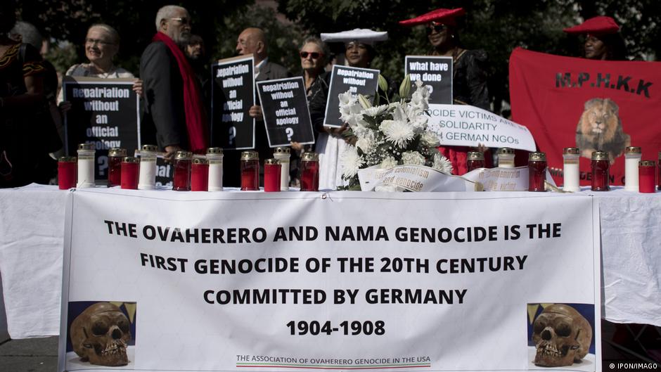 Demonstrators with placards at a rally against the exclusion of members from Namibia on the occasion of the return of bones to Namibia during a memorial service of the EKD and the Namibian partner churches and ceremony in front of the Franzoesische Friedrichstadtkirche in Berlin