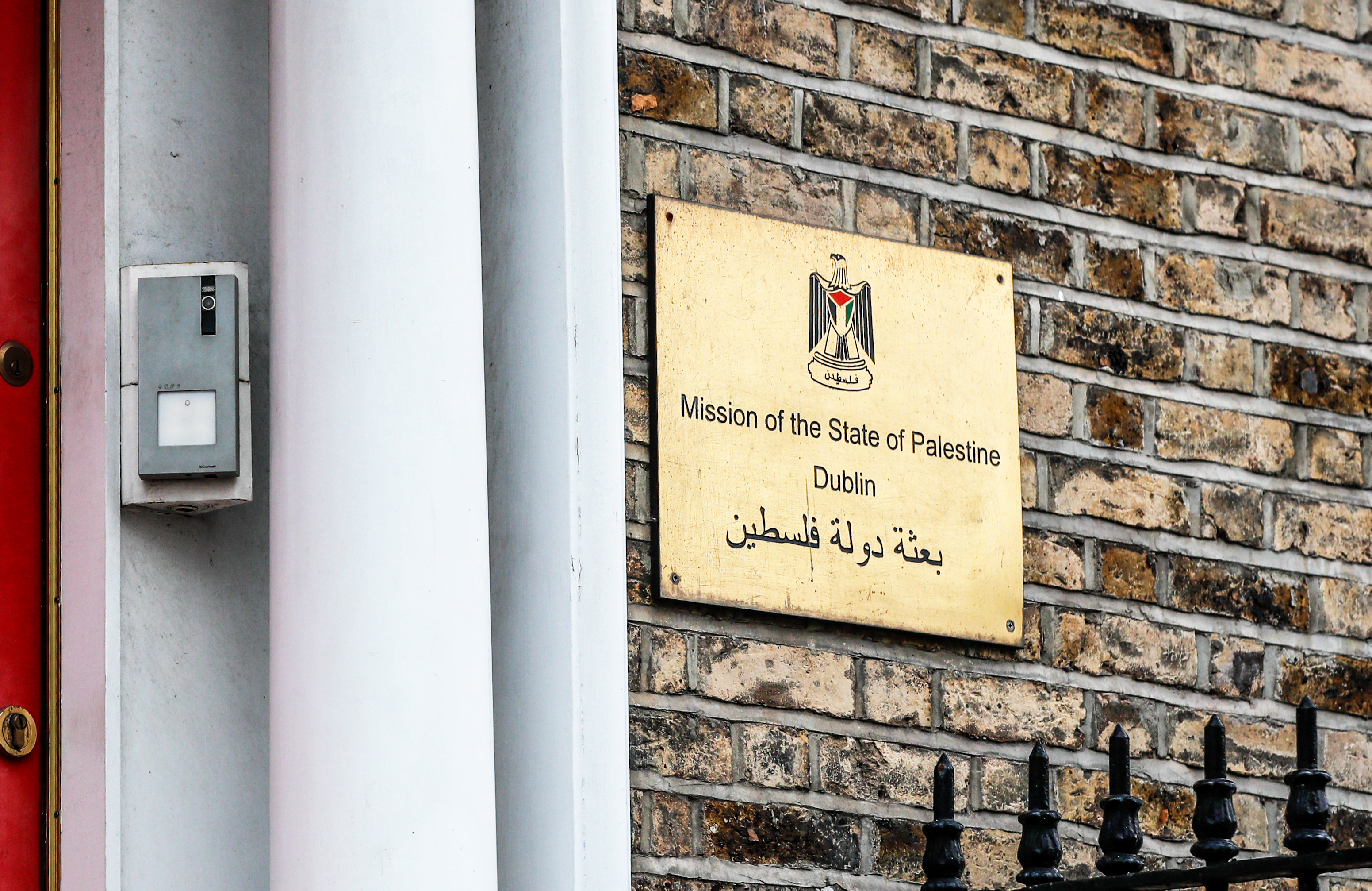 View of a golden sign on a house wall that reads "Mission of the State of Palestine Dublin" in English and Arabic.