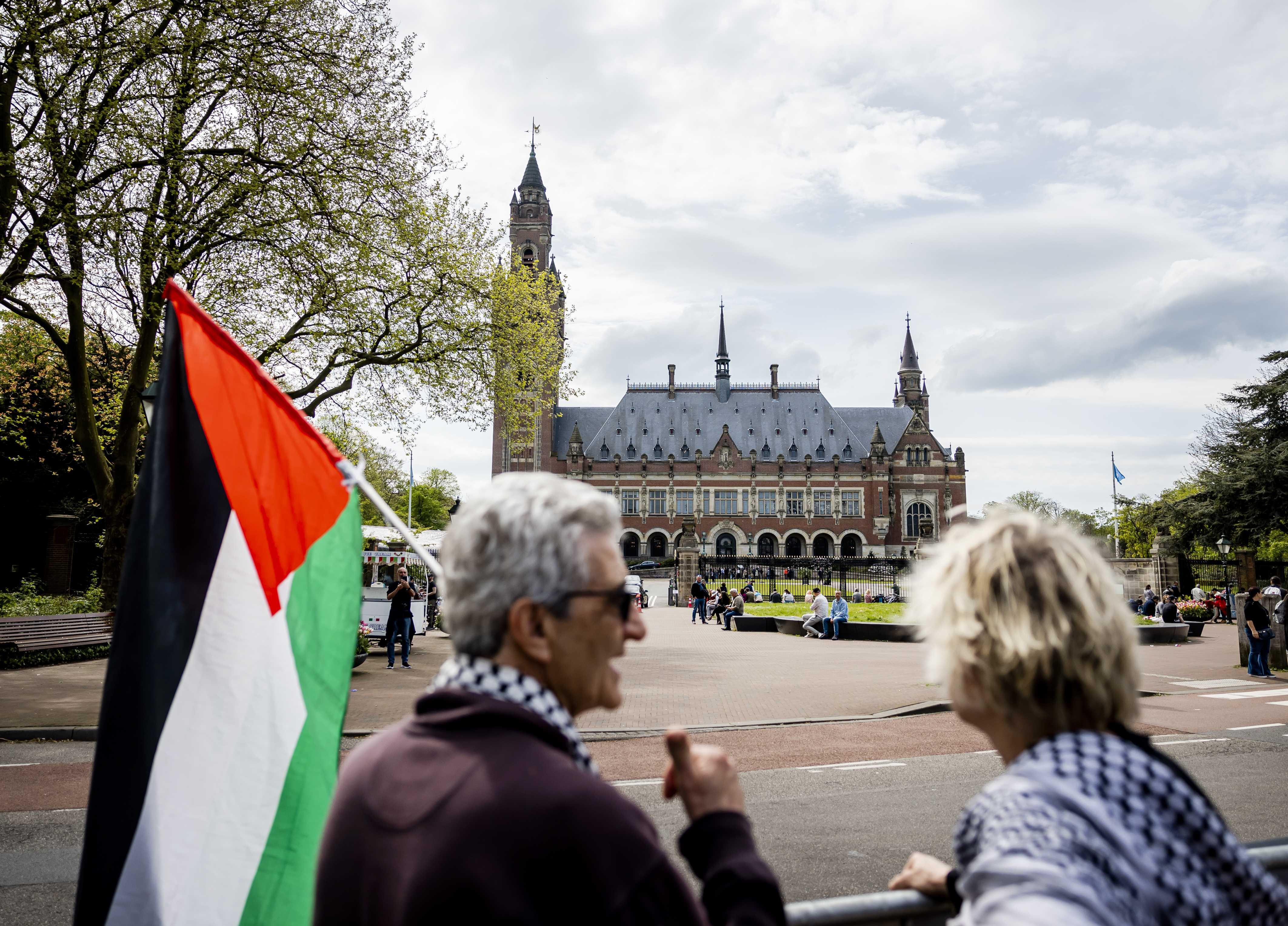 A man with a Palestinian flag and a woman stand before the International Criminal Court in The Hague