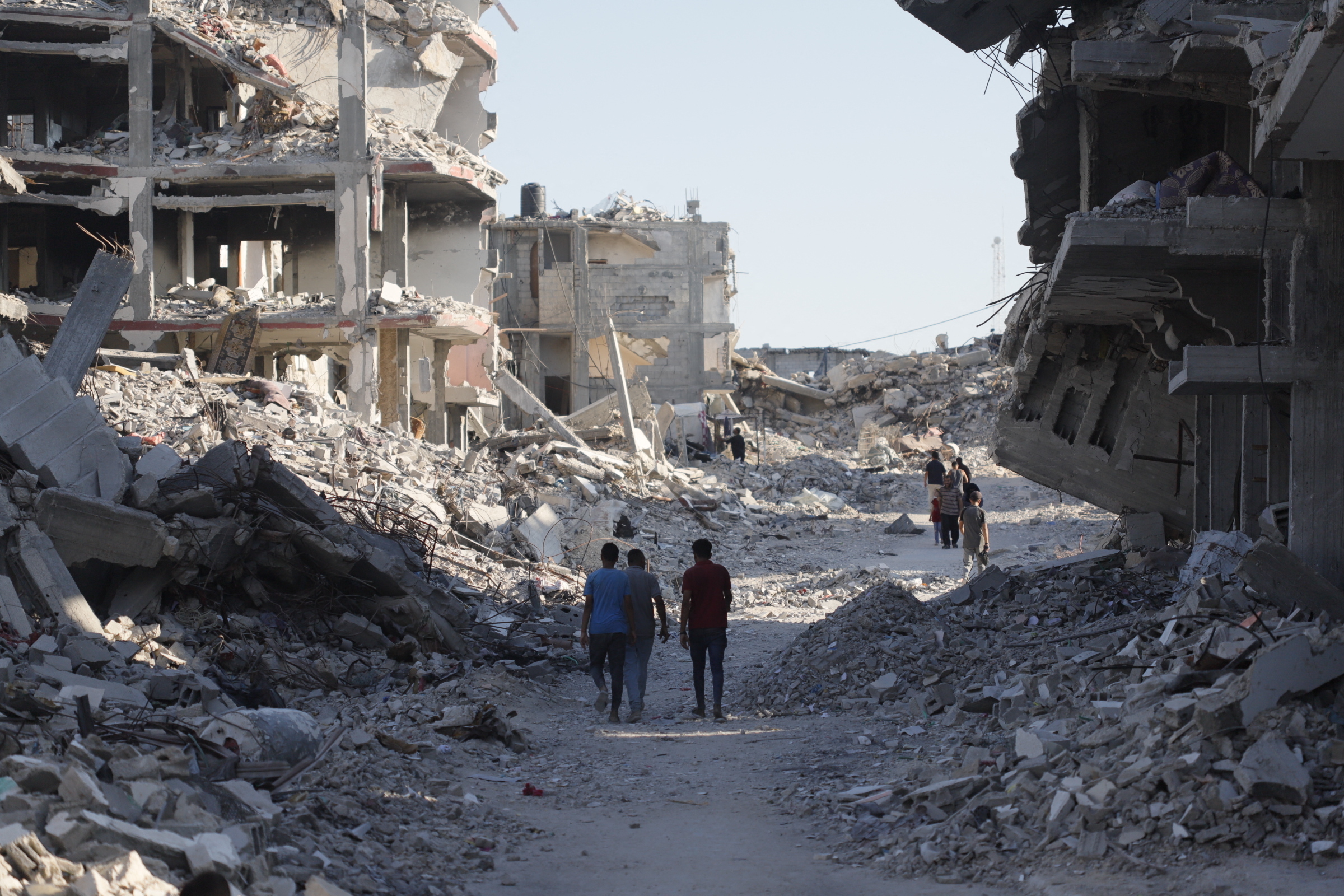 Die Aufnahme zeigt das Ausmaß der Zerstörung in Gaza und zwei Menschen, die zwischen völlig zerstörten Gebäuden und Trümmern laufen.