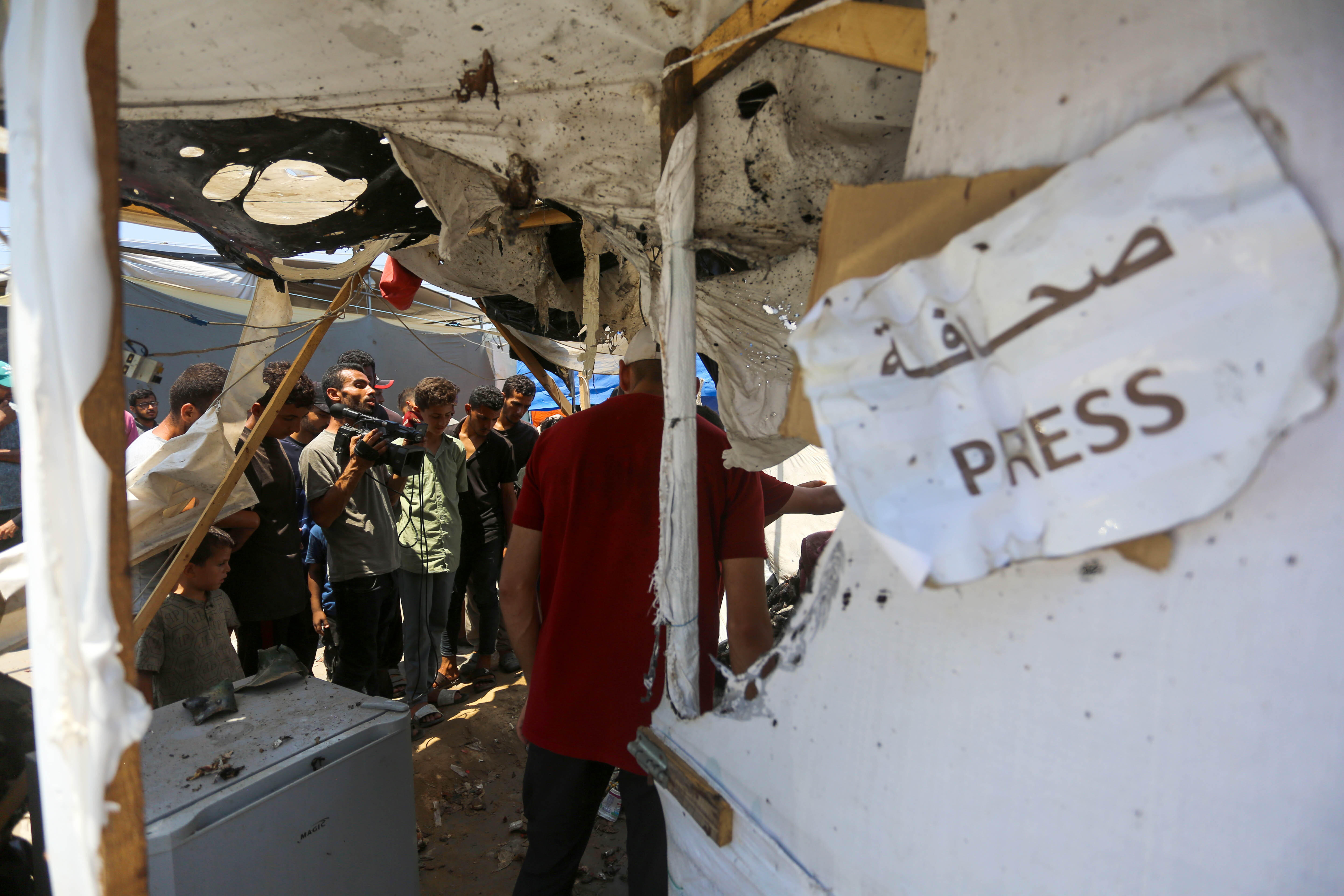 Blick auf ein zerstörtes Zelt in Gaza. Im Vordergrund hängt ein Zetell auf dem in arabischer und englischer Schrift "Presse" steht. Im Hintergrund sind Journalisten zu sehen.