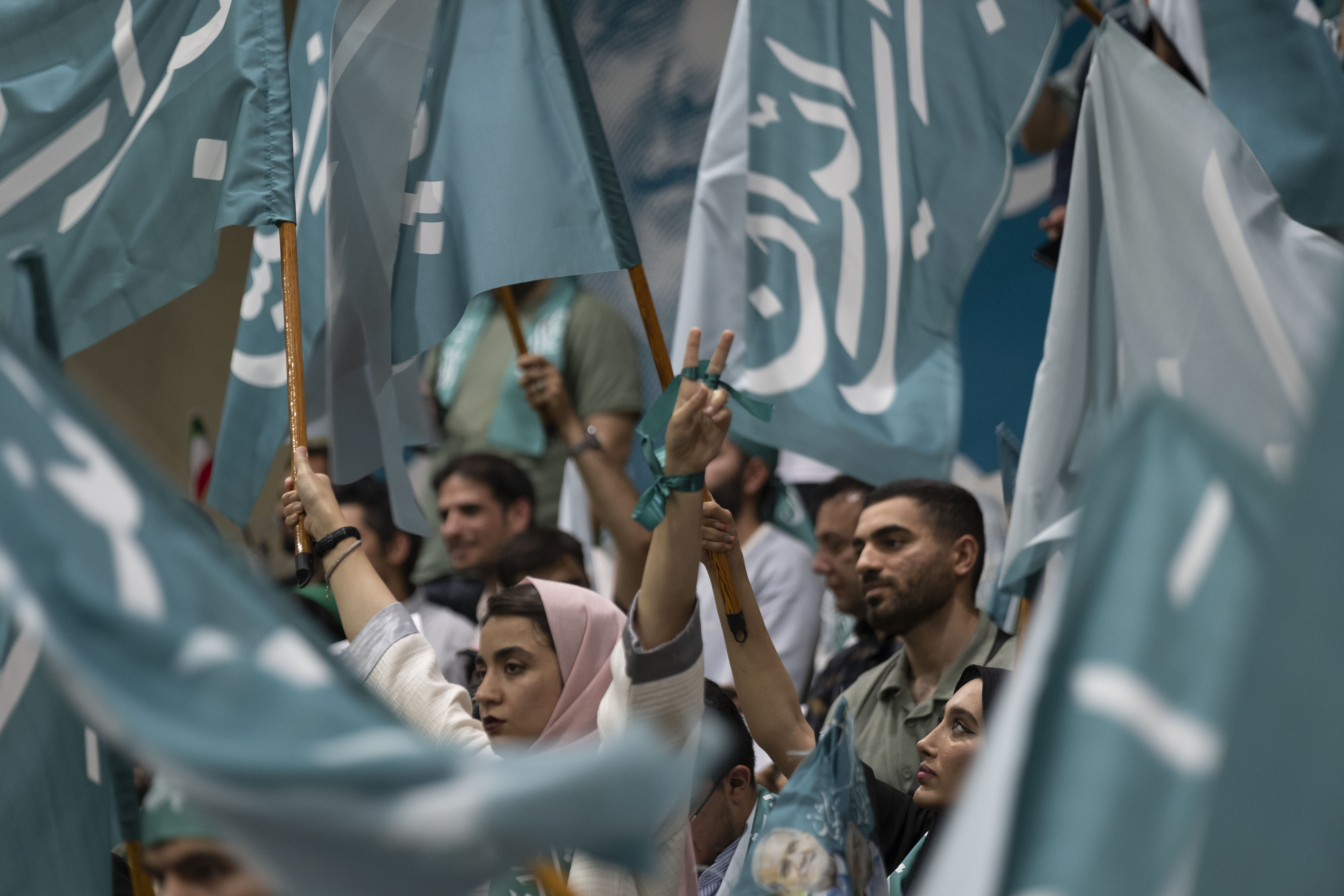 Unterstützer des iranischen Präsidenten Peseschkian schwingen blaue Fahnen und zeigen das "Victory"-Zeichen während seines Wahlkampfes