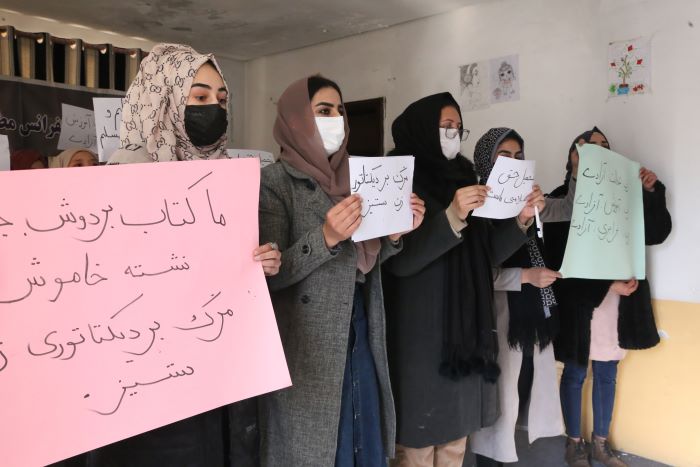 Students hold up posters in a protest against a law banning women from attending university.