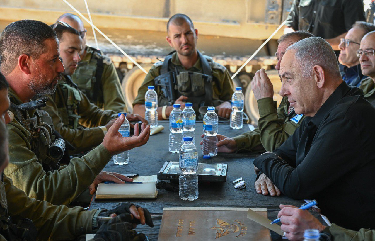 Netanyahu sits round a table with a group of male generals.