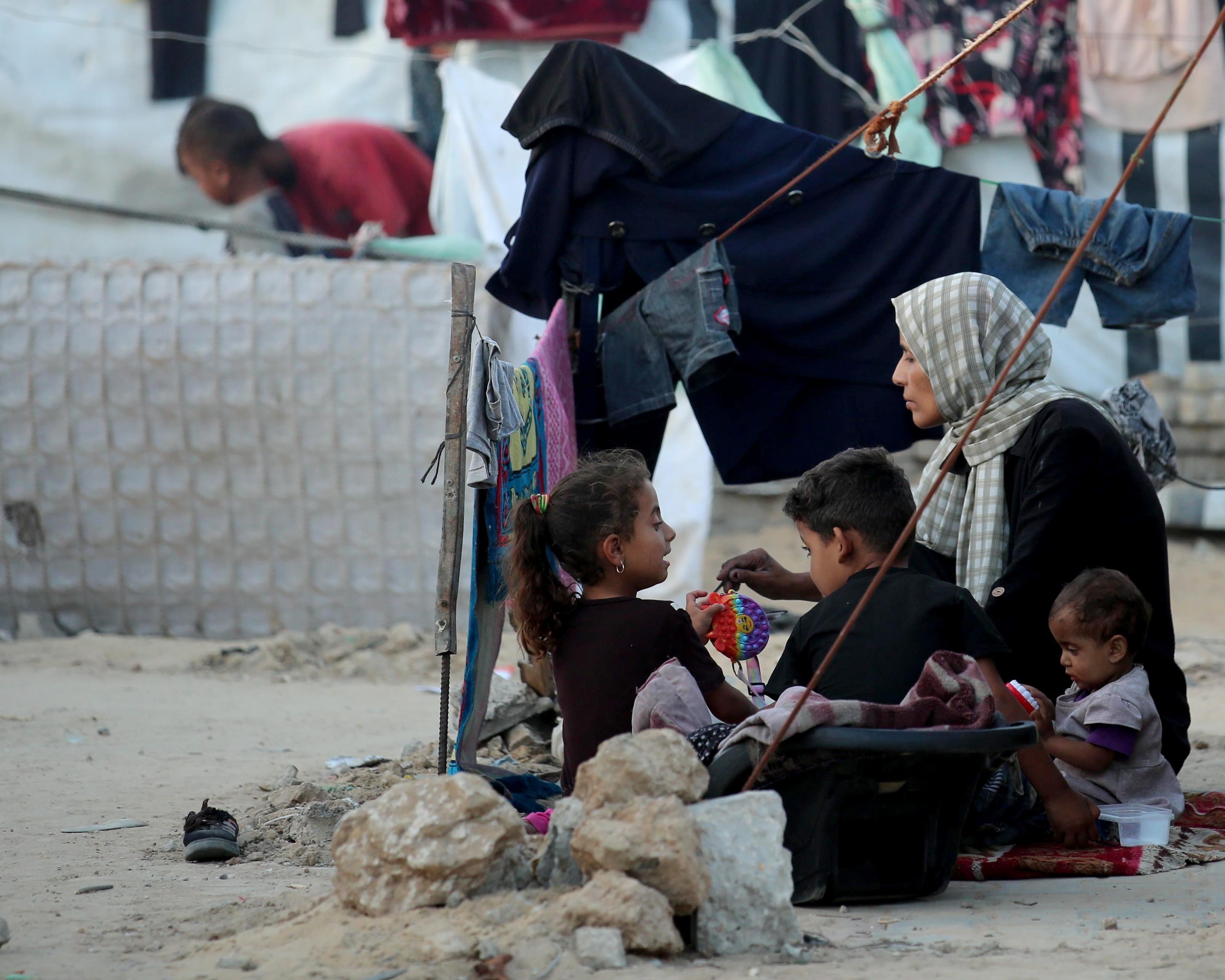 A mother sits with her children on the floor in a refugee camp in Gaza