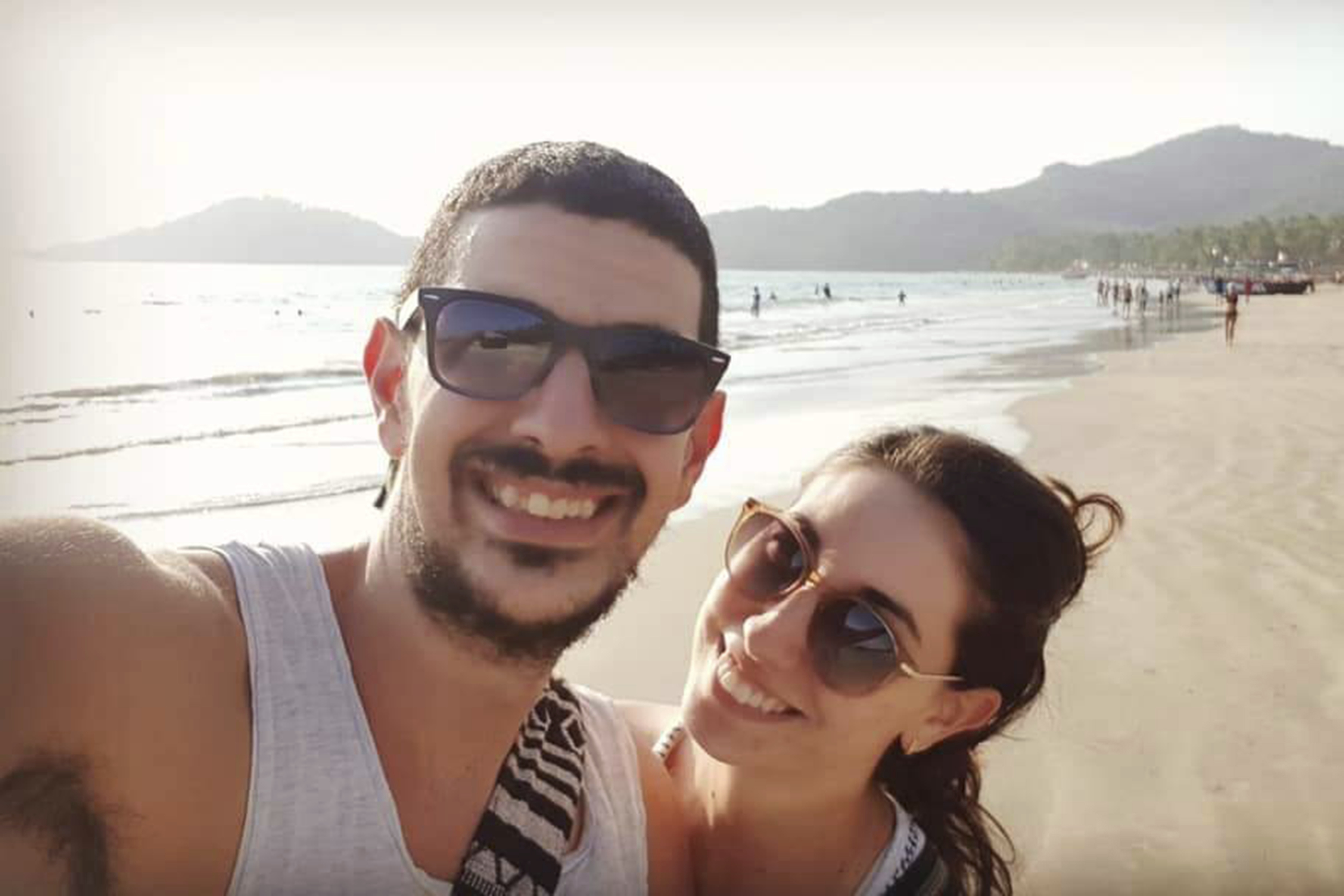 Selfie of a couple at the beach. They wear sunglasses.