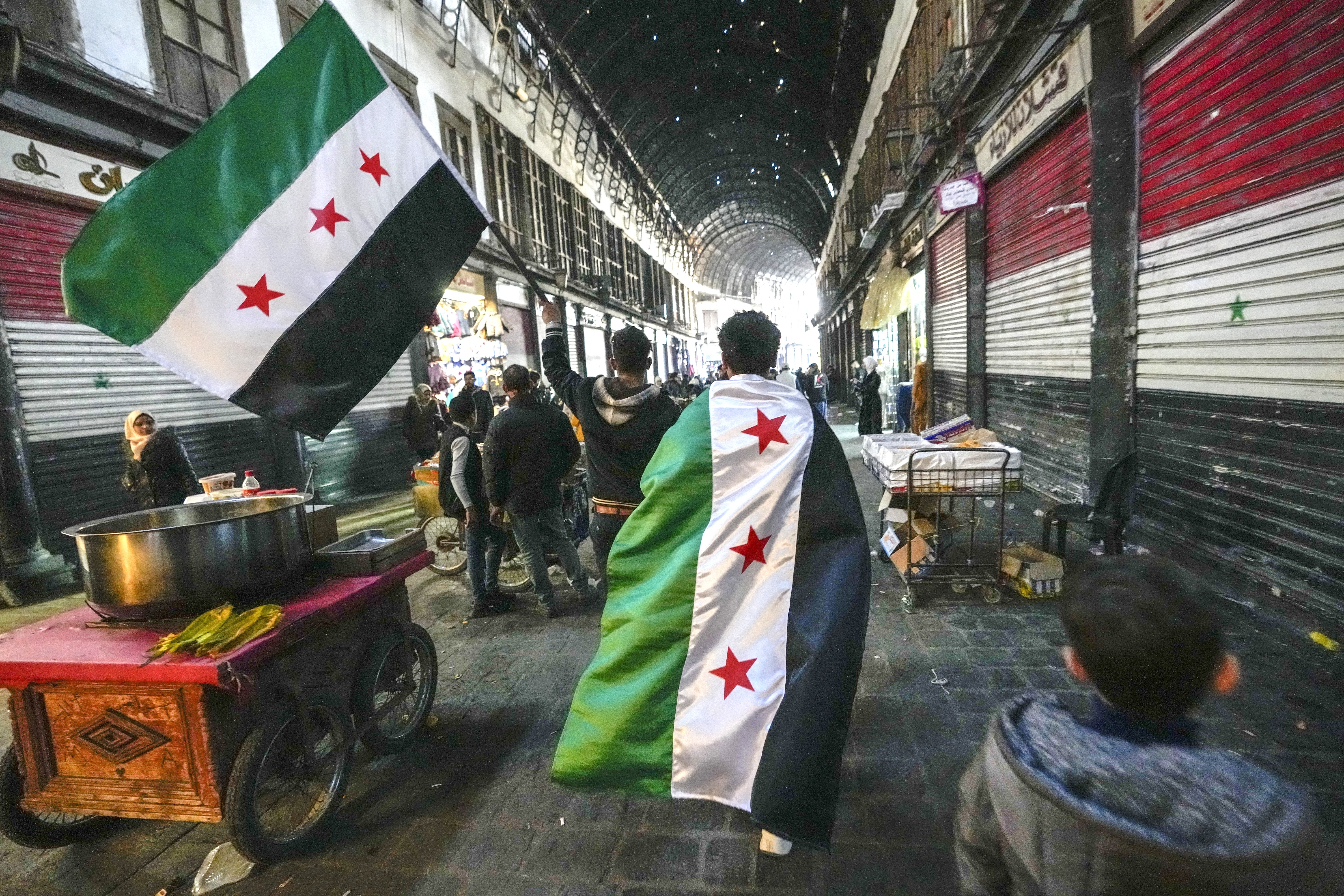 Anhänger der Opposition tragen am Dienstag, dem 10. Dezember 2024, auf dem Al-Hamidiyeh-Markt in der von einer Stadtmauer umgebenen Altstadt von Damaskus, Syrien, Fahnen der Opposition.(Foto: picture alliance / AP| Hussein Malla)