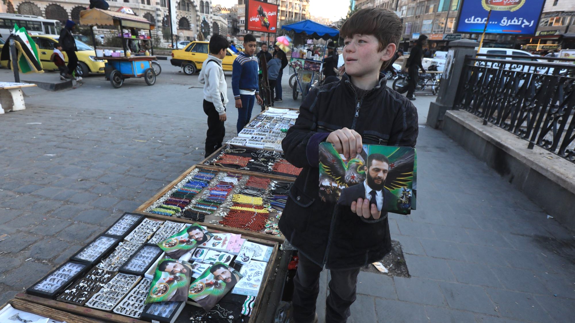 A child holds a poster of a man with suit.